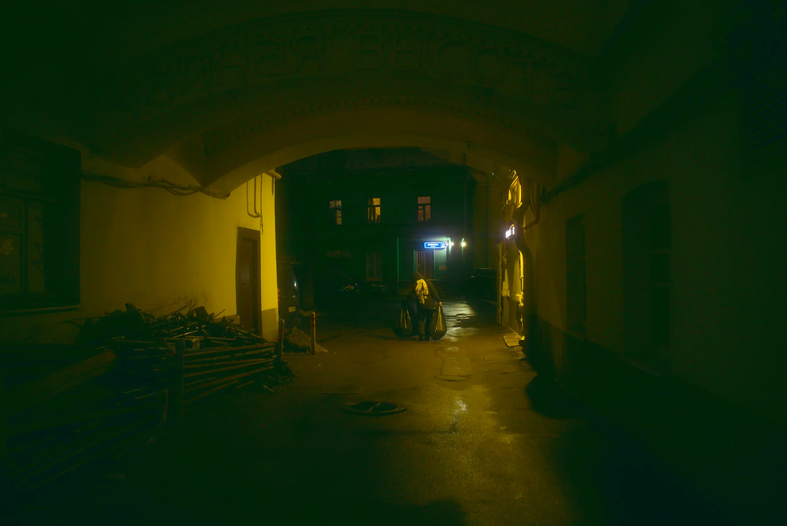 A man taking out the trash from some restaurant in a dark alley